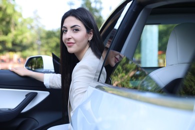 Photo of Woman getting out of modern car outdoors
