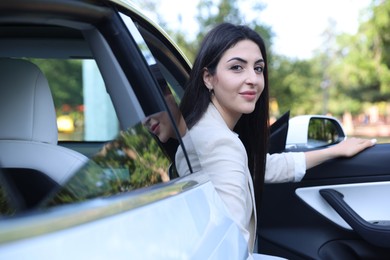 Photo of Woman getting out of modern car outdoors
