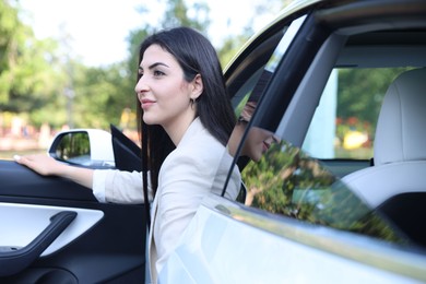 Photo of Woman getting out of modern car outdoors