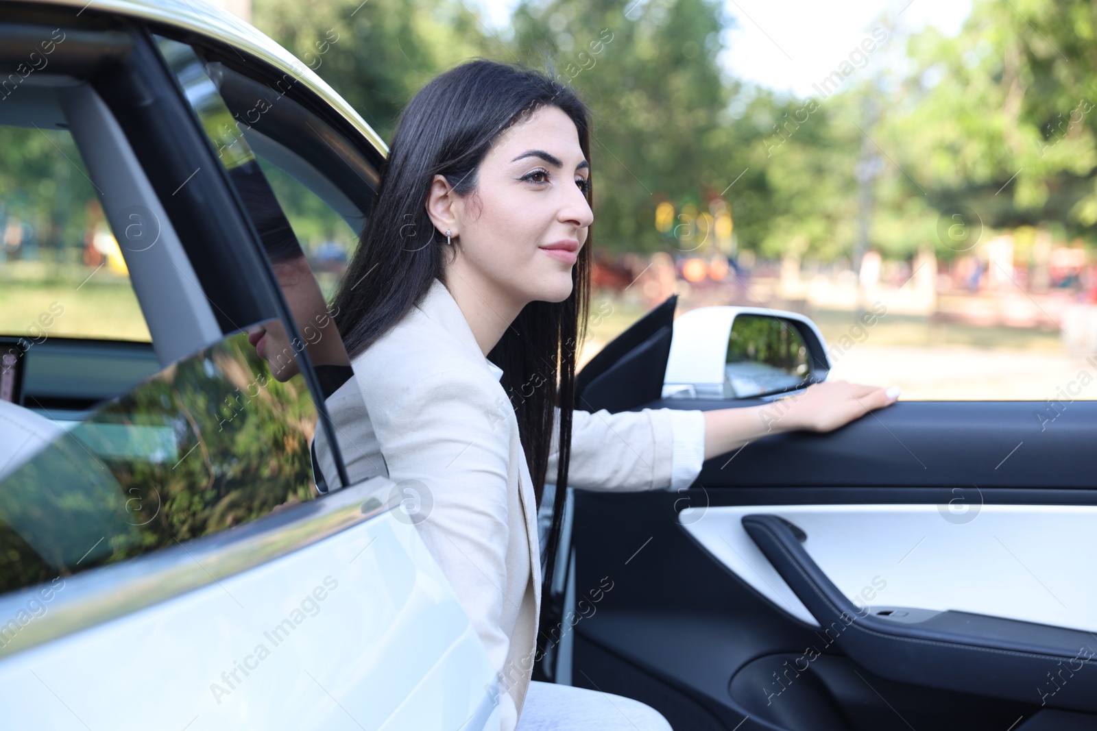 Woman getting out of modern car outdoors Photo of Woman getting out of modern car outdoors