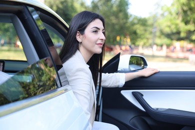 Photo of Woman getting out of modern car outdoors
