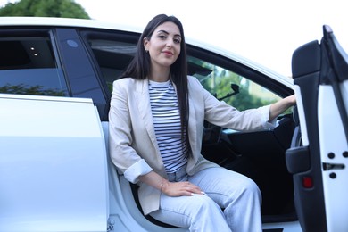 Photo of Woman getting out of modern car outdoors, low angle view