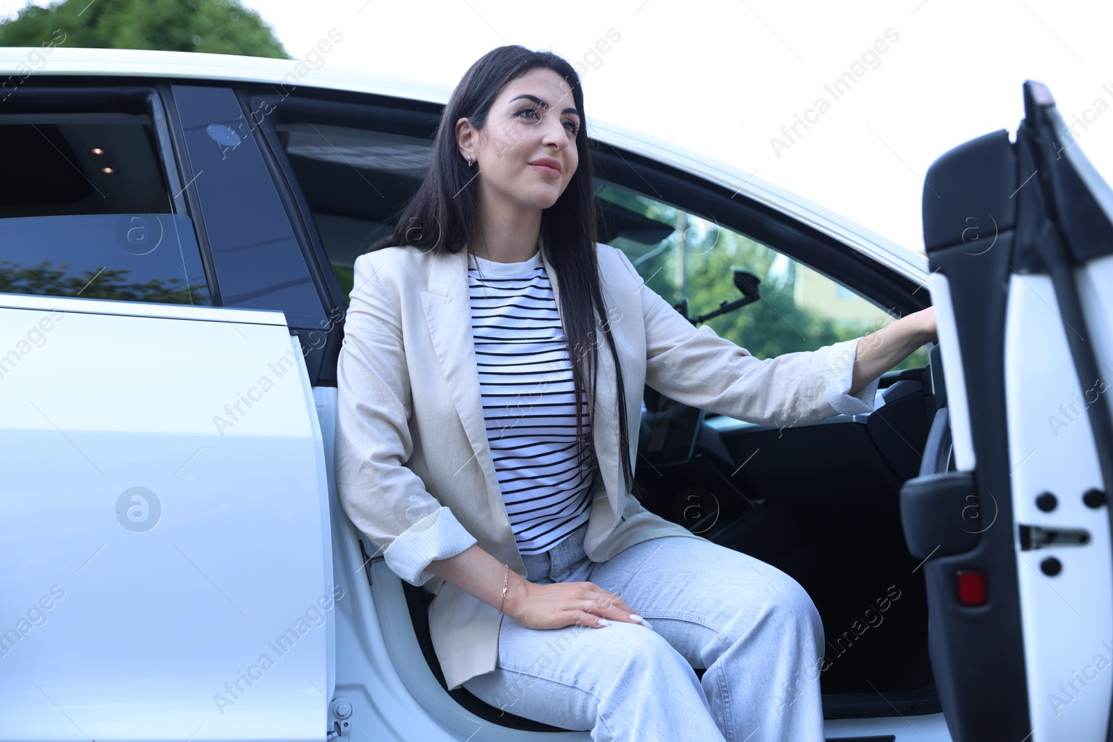 Woman getting out of modern car outdoors, low angle view Photo of Woman getting out of modern car outdoors, low angle view