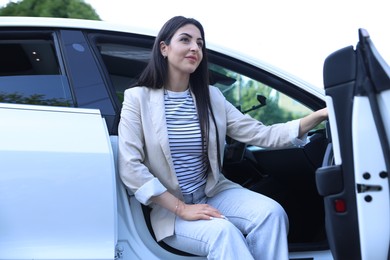 Photo of Woman getting out of modern car outdoors, low angle view