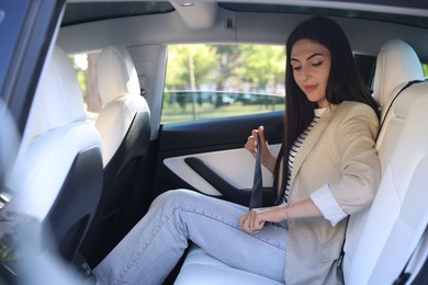 Photo of Woman fastening seat belt in modern car, view from outside