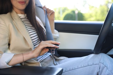 Photo of Woman fastening seat belt in modern car, closeup