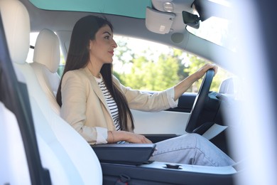 Photo of Woman behind steering wheel of modern car, view from outside