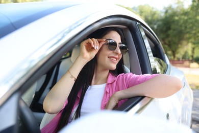 Photo of Woman behind steering wheel of modern car, view from outside