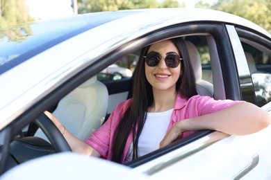 Photo of Woman behind steering wheel of modern car, view from outside