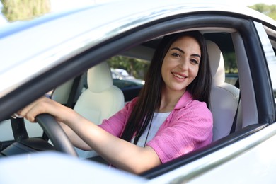 Photo of Woman behind steering wheel of modern car, view from outside