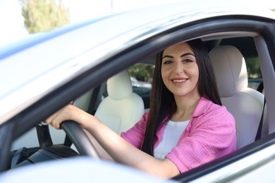 Photo of Woman behind steering wheel of modern car, view from outside