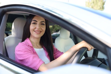 Photo of Woman behind steering wheel of modern car, view from outside