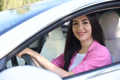 Photo of Woman behind steering wheel of modern car, view from outside