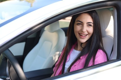 Photo of Woman behind steering wheel of modern car, view from outside