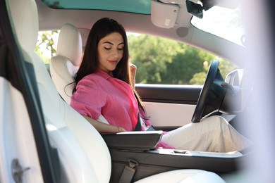 Photo of Woman fastening seat belt in modern car, view from outside