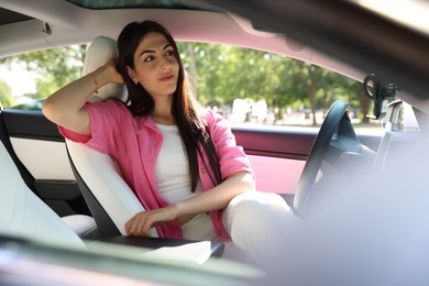 Photo of Beautiful woman sitting in modern car, view from outside
