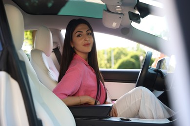 Photo of Beautiful woman sitting in modern car, view from outside