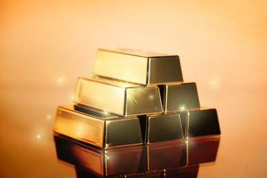 Image of Stacked shiny gold bars on color background