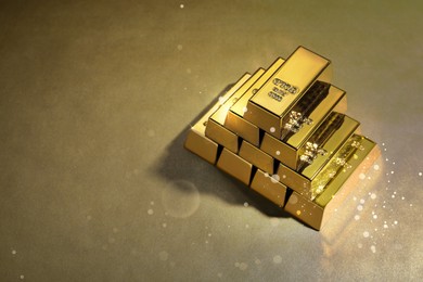 Image of Stacked shiny gold bars on color background. Space for text