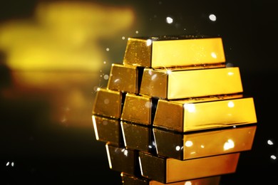 Image of Stacked shiny gold bars on mirror surface. Space for text