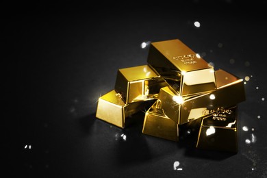 Image of Shiny gold bars on black background. Space for text