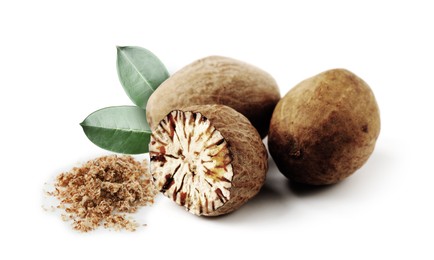 Image of Nutmeg seeds with green leaves on white background. Aromatic spice