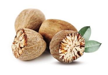 Image of Nutmeg seeds with green leaves on white background. Aromatic spice