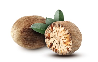 Image of Nutmeg seeds with green leaves on white background. Aromatic spice