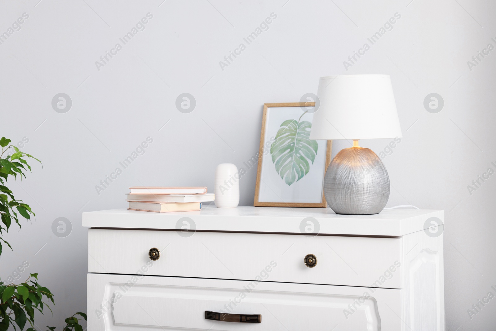 Different decor on white chest of drawers indoors Photo of Different decor on white chest of drawers indoors