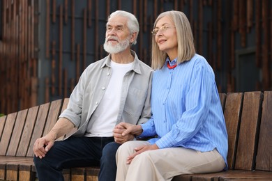 Photo of Lovely senior couple on bench near building outdoors