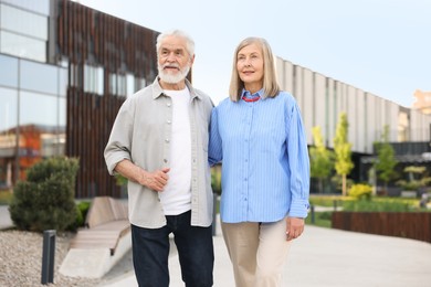 Photo of Lovely senior couple walking together on city street