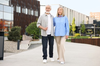 Photo of Lovely senior couple walking together on city street