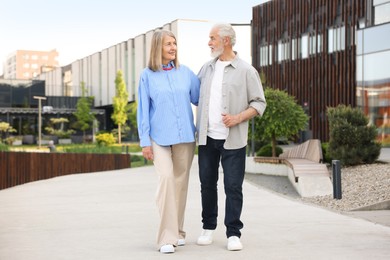 Photo of Lovely senior couple walking together on city street