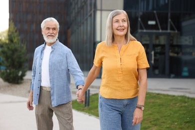 Photo of Lovely senior couple walking together on city street