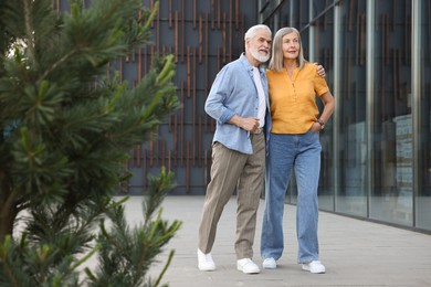 Photo of Lovely senior couple walking together near building outdoors