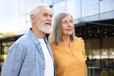 Photo of Lovely senior couple walking together near building outdoors