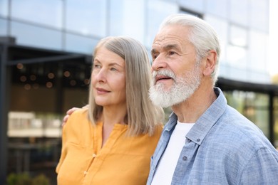 Photo of Lovely senior couple walking together near building outdoors