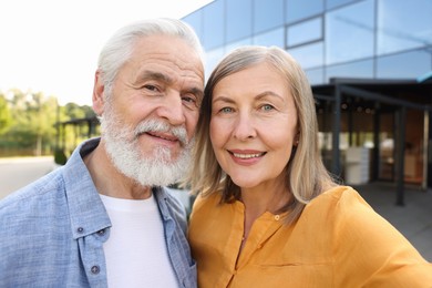 Photo of Lovely senior couple taking selfie near building outdoors