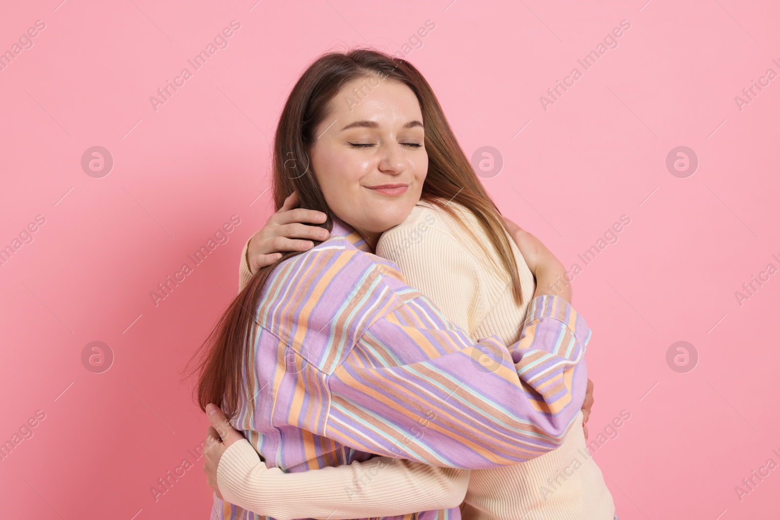 Two happy friends hugging on pink background Photo of Two happy friends hugging on pink background