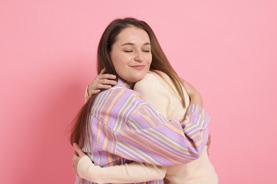 Photo of Two happy friends hugging on pink background