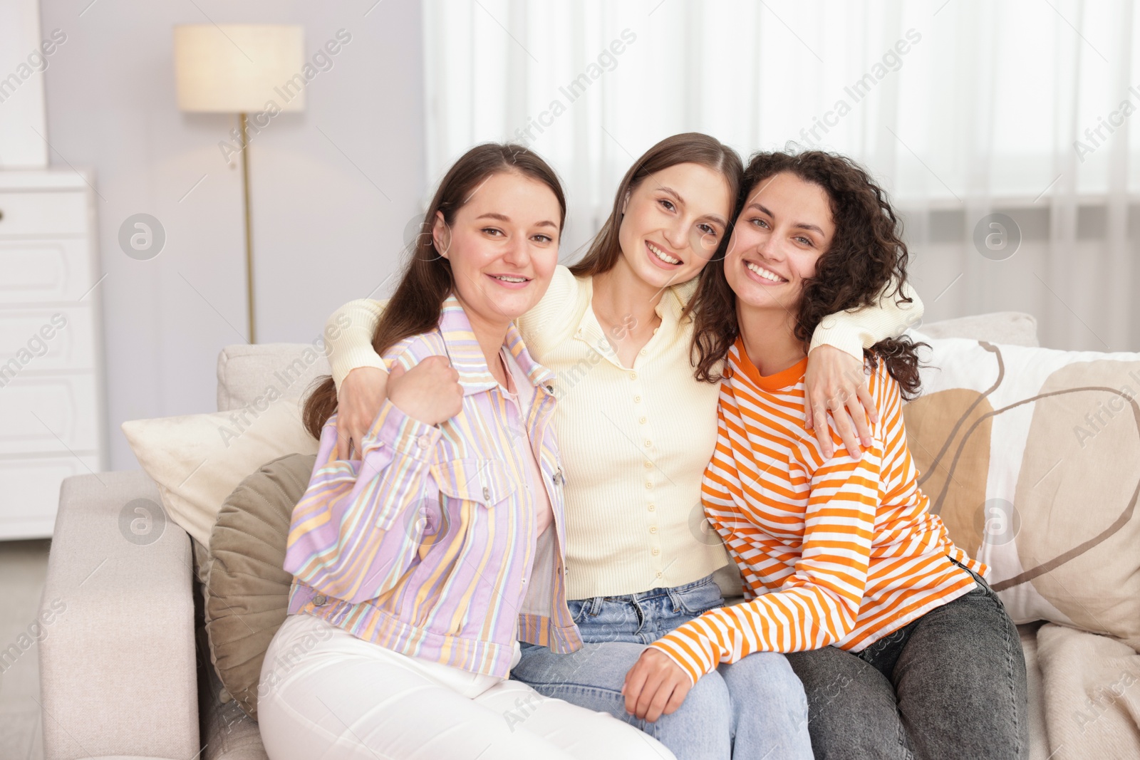 Photo of Friends hugging each other on sofa indoors
