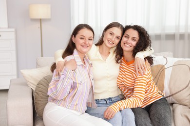 Photo of Friends hugging each other on sofa indoors