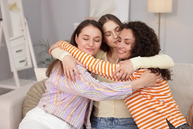 Photo of Friends hugging each other on sofa indoors
