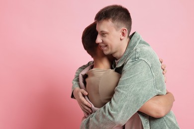 Photo of Two happy friends hugging on pink background, space for text