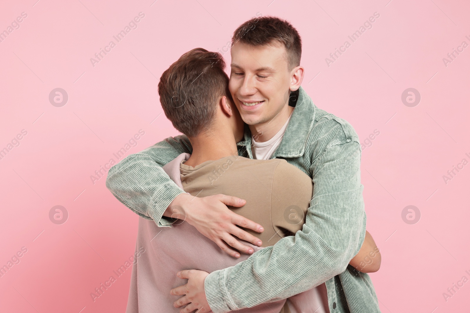 Two happy friends hugging on pink background Photo of Two happy friends hugging on pink background