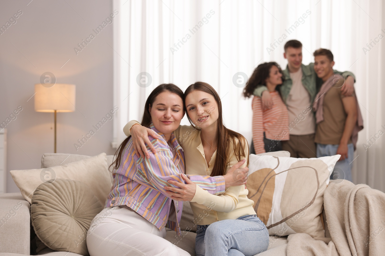 Friends hugging on sofa indoors, selective focus Photo of Friends hugging on sofa indoors, selective focus