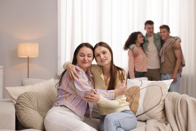 Photo of Friends hugging on sofa indoors, selective focus