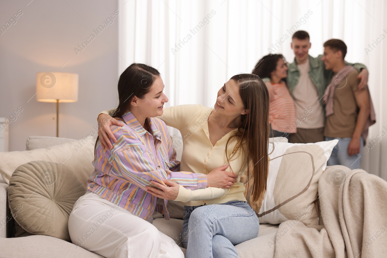 Photo of Friends hugging on sofa indoors, selective focus