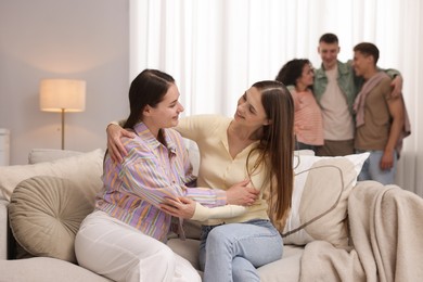 Photo of Friends hugging on sofa indoors, selective focus