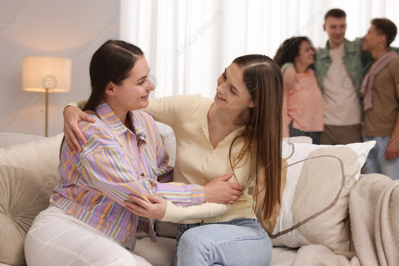 Friends hugging on sofa indoors, selective focus Photo of Friends hugging on sofa indoors, selective focus